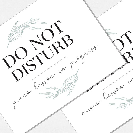 Two overlapping paper prints. The top print reads 'DO NOT DISTURB' with 'piano lesson in progress' below, and the bottom print reads 'DO NOT DISTURB' with 'music lesson in progress' below. Decorated with pale green willow leaf illustrations, arranged on a neutral colored background.
